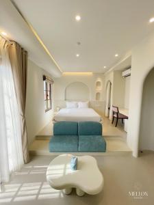a bedroom with a large bed and a blue couch at Mellon OASIS Phu Quoc in Phú Quốc