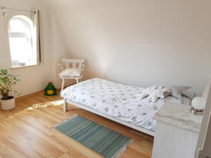 een witte slaapkamer met een bed en een stoel bij Muschelkästchen OG in Tönning