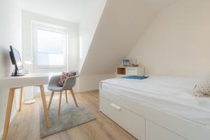 a white bedroom with a desk and a bed at 36 Grad in Garding