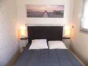 een slaapkamer met een bed met twee lampen aan beide zijden bij Saint Georges de Didonne - APPARTEMENT en rez-de-chaussée - proche PLAGE in Saint-Georges-de-Didonne