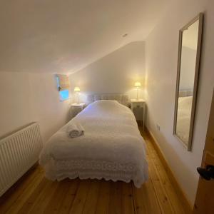a bedroom with a large white bed with two lamps at Immaculate historical 2-Bed Cottage in The Fens in Lutton