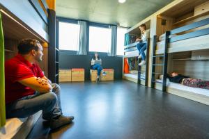 a man sitting on a bench in a room with bunk beds at The People - Paris Marais in Paris