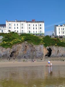a couple of people standing in the water at the beach at Clarence House Hotel in Tenby