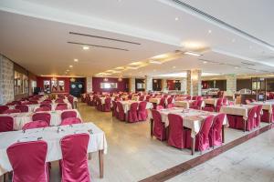 a banquet hall with white tables and red chairs at Hotel Palas in Petrovac na Moru