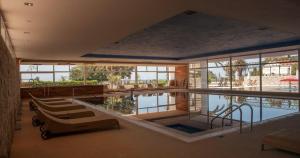 a swimming pool in a building with chairs and tables at Hotel Palas in Petrovac na Moru