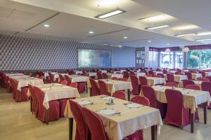 a banquet hall with tables and red chairs and a screen at Hotel Palas in Petrovac na Moru