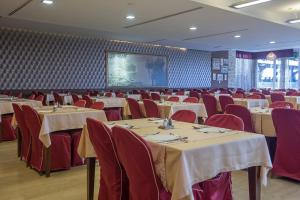 a banquet hall with tables and chairs and a screen at Hotel Palas in Petrovac na Moru