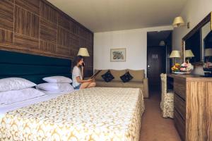 a woman sitting on a bed in a hotel room at Hotel Palas in Petrovac na Moru