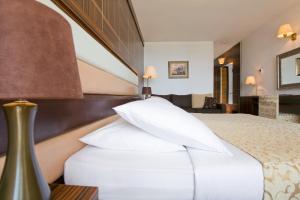 a hotel room with a bed with white pillows at Hotel Palas in Petrovac na Moru