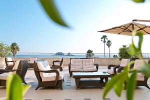 a patio with chairs and tables and an umbrella at Hotel Palas in Petrovac na Moru