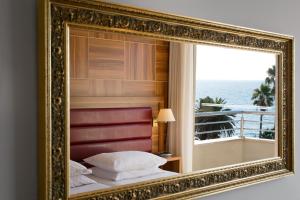 a mirror reflecting a bedroom with a view of the ocean at Hotel Palas in Petrovac na Moru