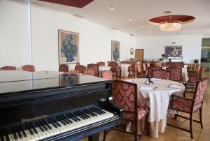 a dining room with a piano and a table and chairs at Hotel Palas in Petrovac na Moru
