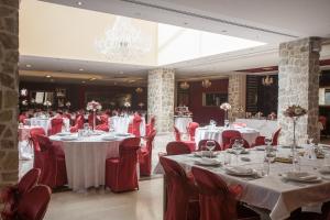a dining room with white tables and red chairs at Hotel Palas in Petrovac na Moru