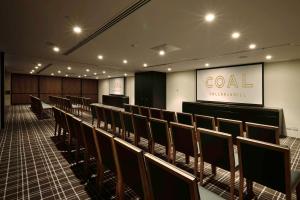 une salle de conférence avec des chaises et un panneau sur le mur dans l'établissement Hilton Adelaide, à Adélaïde