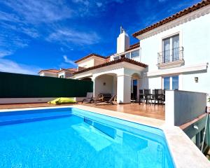 a villa with a swimming pool in front of a house at Casa Beloura between the sea and the mountains in Sintra