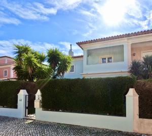 a house with a white fence and palm trees at Casa Beloura between the sea and the mountains in Sintra