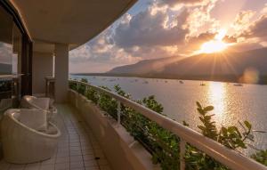 a balcony with a view of the water at sunset at Hilton Cairns in Cairns