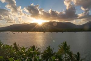 a sunset over a lake with mountains in the background at Hilton Cairns in Cairns
