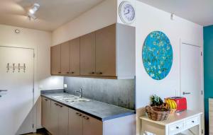 uma cozinha com um lavatório e um relógio na parede em Duin en zee em Bredene