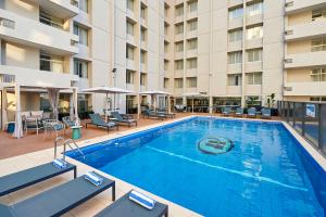 ein großer Pool mit Stühlen und ein Hotel in der Unterkunft Parmelia Hilton Perth in Perth
