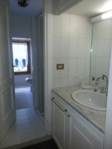 a white bathroom with a sink and a mirror at Cascina Ciosse B&B in Grognardo