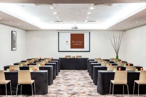 una sala de conferencias con mesas, sillas y una pantalla en DoubleTree by Hilton Melbourne, en Melbourne
