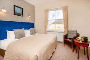 a bedroom with a bed and a window and a chair at The Clifton Hotel Bristol in Bristol