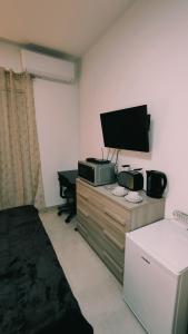 a room with a television on a dresser with a bed at Fairwinds - Double Room with Ensuite - Luqa Airport - Self Check In & Out available in Luqa