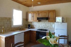a kitchen with wooden cabinets and a white refrigerator at Les charmes en périgord noir proche de Sarlat in Paulin