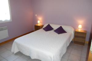 sypialnia z białym łóżkiem z fioletowymi poduszkami w obiekcie Les charmes en périgord noir proche de Sarlat w mieście Paulin