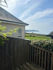 a wooden fence next to a house with a view of the ocean at The Surf House (Widemouth Bay) in Bude