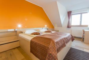 1 dormitorio con 1 cama con pared de color naranja en Lake Peak Apartments, Ribniško Pohorje, en Ribnica na Pohorju