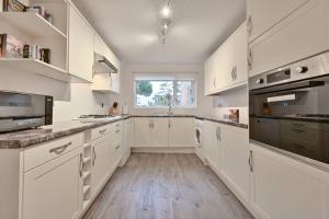 cocina blanca con armarios blancos y ventana en Spacious Sandbanks Apartment near Beach and Bars with Free Parking, en Poole