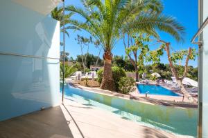 a view of a swimming pool with palm trees at Tacande Portals in Portals Nous