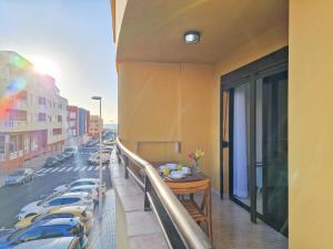 Un balcón con una mesa y coches en una calle en MEDANO4YOU Brisas Del Atlantico en El Médano
