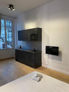 a room with a kitchen with black cabinets and a tv at Studio Grand Rex in Paris