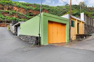 un edificio verde con una puerta naranja en una calle en Finca Candelario sc de La Palma en Santa Cruz de la Palma