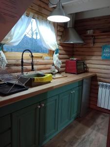 Mini Casa de Troncos en el Sur في سان مارتين دي لوس أندس: مطبخ مع دواليب خضراء ومغسلة ونافذة