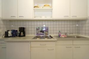 a kitchen with white cabinets and a sink at Haus Sylter Welle 9-92a OB in Westerland (Sylt)