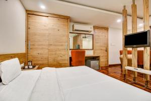 a bedroom with a white bed and a tv at FabHotel Manjeet in Bhopal