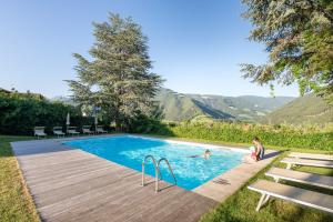 two people in a swimming pool with mountains in the background at Baumgartnerhof in Naz-Sciaves