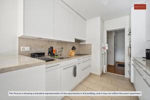 uma cozinha branca com armários e electrodomésticos brancos em Beautiful Boutique Apartment DRAHTZUG16 em Zürich