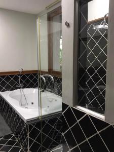 a black and white bathroom with a tub and a mirror at Plumeria Villa Thalang in Ban Pak Lak