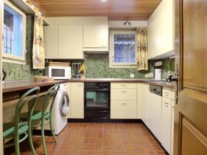 een keuken met witte kasten en een wasmachine en droger bij Holiday Home Chalet Marietta by Interhome in Kandersteg