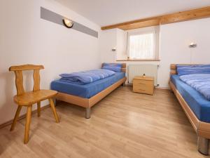 a bedroom with two beds and a wooden chair at Apartment Fürderer by Interhome in Eisenbach +8 photos