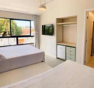 a bedroom with two beds and a large window at Liiv Hub - Natal PontaNegra in Natal