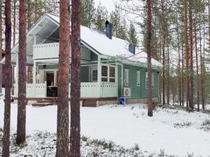 ein grünes Haus im Wald im Schnee in der Unterkunft Holiday Home Huuhkalinna by Interhome in Syöte