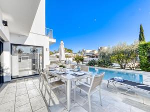 een patio met een tafel en stoelen naast een zwembad bij Holiday Home Norfeu by Interhome in Empuriabrava