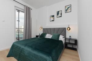 a bedroom with a green bed and a window at Cozy Apartments Warsaw Wola Kasprzaka by Renters in Warsaw