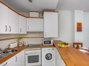 a kitchen with white cabinets and a bowl of fruit on the counter at Apartment Torrealba by Interhome in Fuengirola